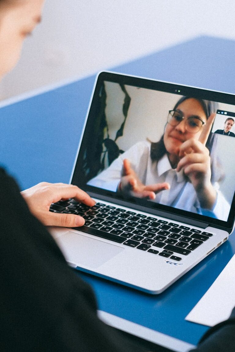 Woman participating in a virtual meeting, taking notes during a video conference on a laptop.