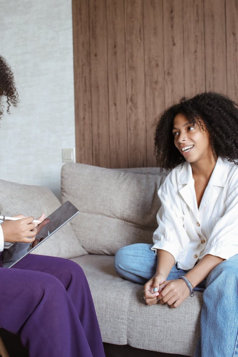 Two women in a friendly conversation on a sofa, showcasing a relaxed atmosphere.